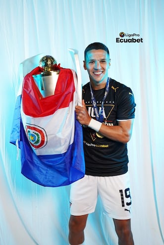 Alex Arce posa con el trofeo de campeón y la bandera paraguaya.