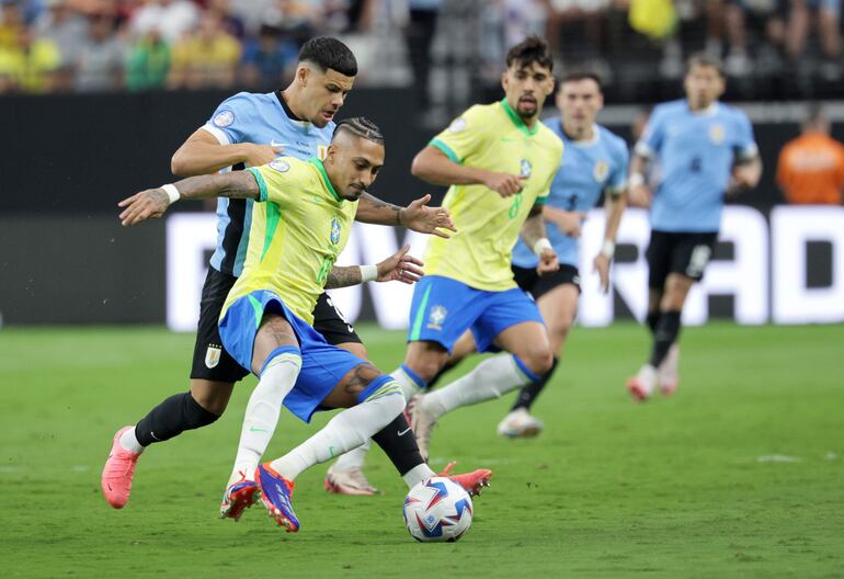 Raphinha Dias de Brasil (C) en acción contra Maximiliano Araujo de Uruguay (L) durante el partido de cuartos de final de la CONMEBOL Copa América 2024 entre Uruguay y Brasil, en Las Vegas, Nevada, EE.UU., el 6 de julio de 2024.