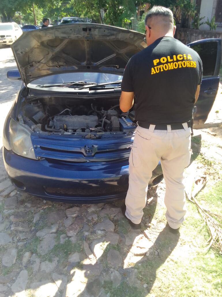 Un efectivo policial de Control de Automotores realiza un peritaje al automóvil Toyota IST azul, que fue recuperado durante el procedimiento. El vehículo había sido denunciado como robado en marzo del año pasado en Asunción.