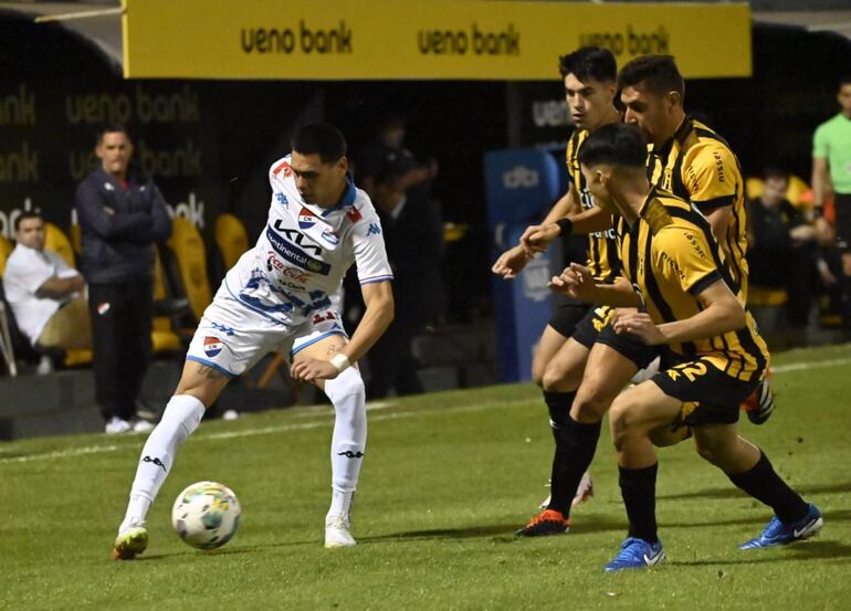 Gustavo Caballero trata de avanzar ante tres jugadores de Guaraní