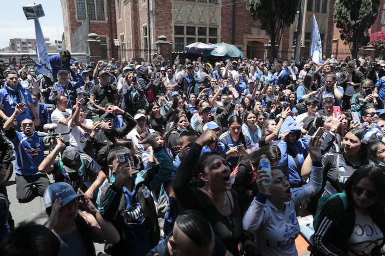 Integrantes de la barra Comandos Azules del equipo colombiano Millonarios alientan afuera del hospital San Ignacio para despedir a Javier Acosta este viernes, en Bogotá (Colombia). 