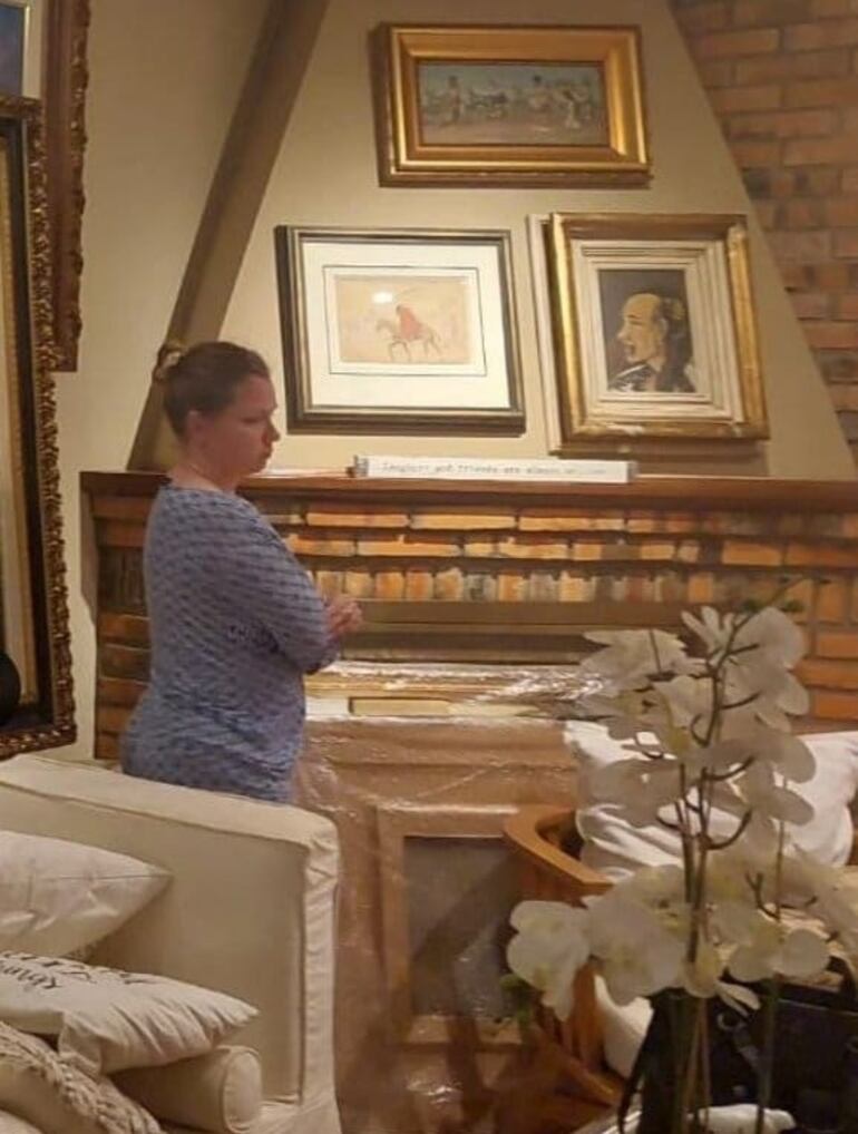 En esta foto tomada en la residencia de Carlos Oleñik Memmel y su pareja Viviana Perini Roth no alcanzan las paredes para colgar sus obras de arte. Al pie de la chimenea se observan más cuadros embalados.