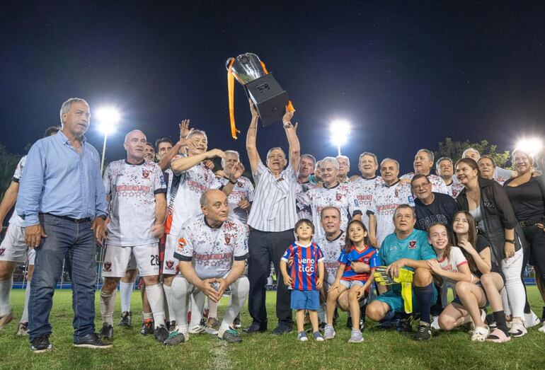 El trofeo de campeón en alto y custodiado por los futbolistas y simpatizantes del equipo de Estrellas del Foro, monarca en el torneo Super Senior del Club Deportivo de Puerto Sajonia.