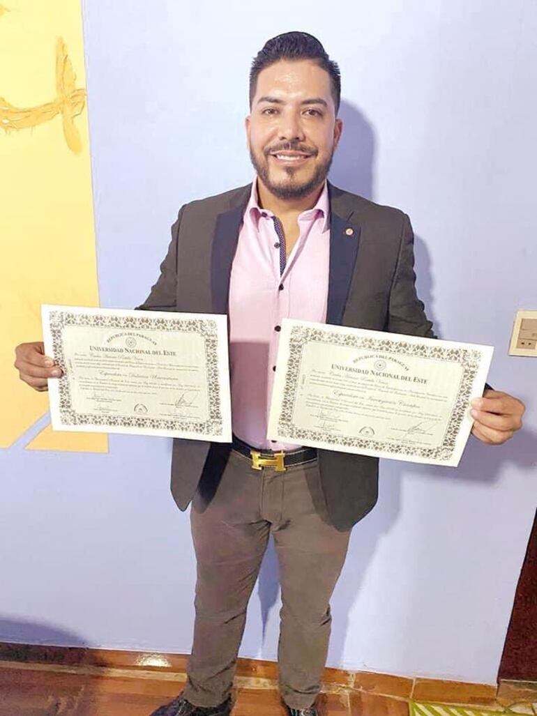 Carlos Portillo exhibiendo dos diplomas universitarios.