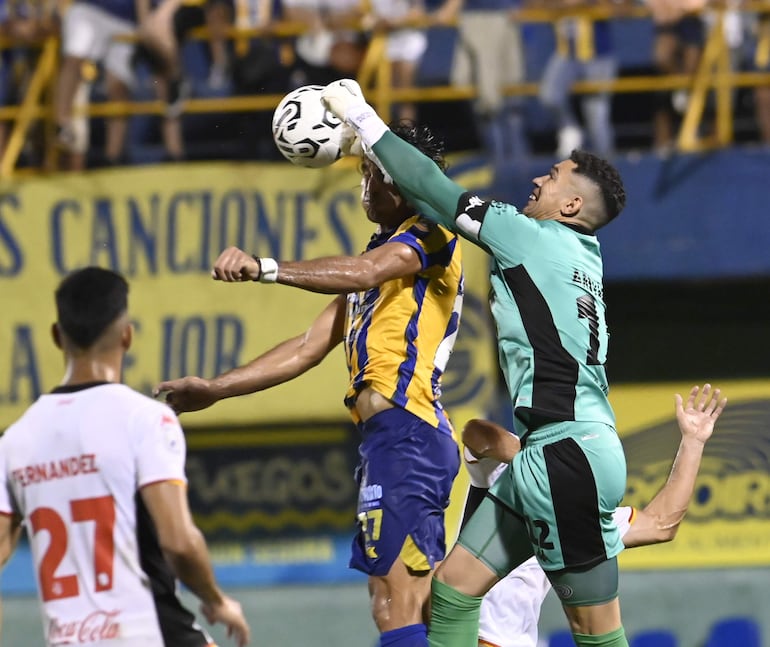 Jorge Benítez intenta ganar de cabeza, pero el arquero Gustavo Arévalos llega primero para despejar el balón.