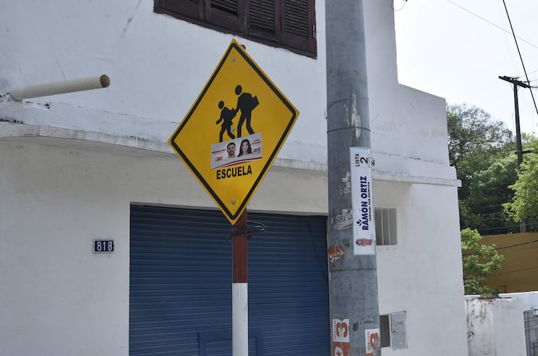 Calcomanía de Óscar "Nenecho" Rodríguez y Guadalupe Aveiro en un cartel de cruce peatonal.