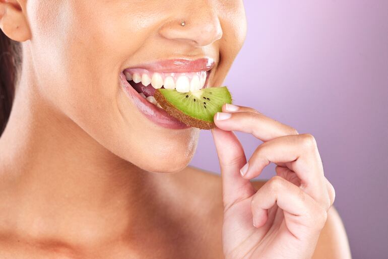 Mujer comiendo kiwi.