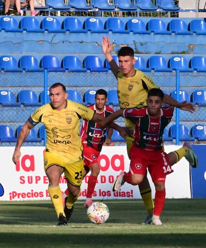 Juan Isidro Nuñez (izq.) intenta defender el balón ante la oposición del rojiverde Juan Francisco Esteche (14).