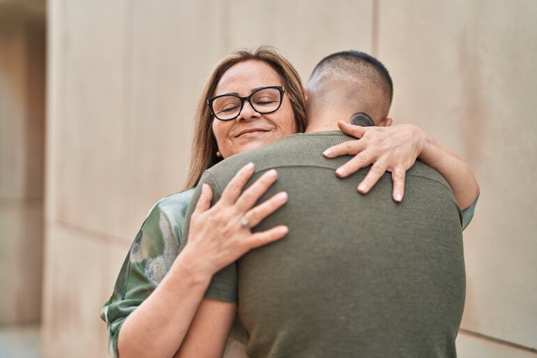 Una mujer abraza a un hombre adulto.