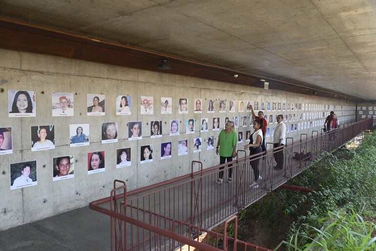 Familiares de víctimas del Ycua  Bolaños recorren un pasillo del memorial, donde observan las fotografías de sus seres queridos.