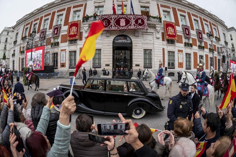 La princesa Leonor, acompañada por la infanta Sofía, a bordo del Rolls Royce Phamton IV y escoltadas por la Guardia Real Motorizada, saluda a los ciudadanos a su paso por la Real Casa de Correos, sede del Gobierno de la Comunidad de Madrid, en su trayecto hacia el Congreso de los Diputados, donde tuvo lugar la jura de la Constitución de la Princesa de Asturias por su mayoría de edad ante las Cortes Generales. (EFE/ Fernando Villar)
