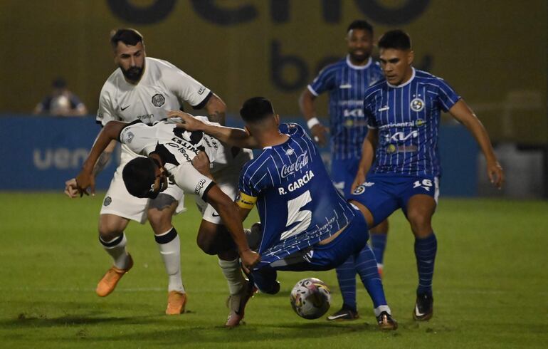 El delantero de Olimpia, Hugo Benítez, y el defensor de Sol de América, Rolando García Guerreño, van al piso luego de disputar por el balón.