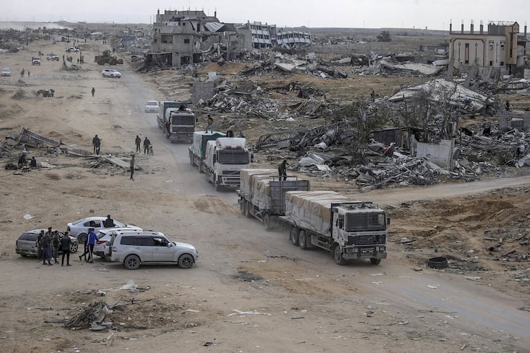 Camiones de ayuda humanitaria pasan por edificios destruidos en medio de una cesación del fuego entre Israel y Hamas, al este de Rafah, sur de la Franja de Gaza.