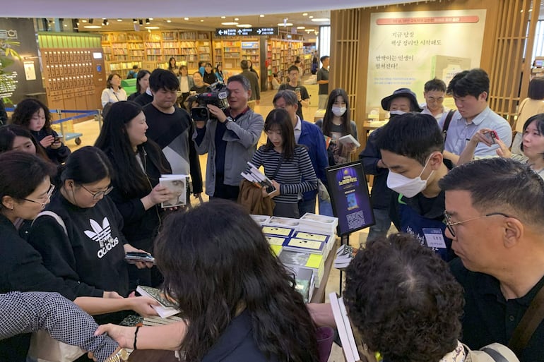 Clientes en la librería principal de la cadena Kyobo, en el distrito de Jongno en Seúl, se agolpan para hacerse con copias de libros de la escritora Han Kang un día después de que la autora fuera galardonada con el premio Nobel de Literatura.