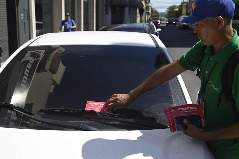 Ordenadores advierten a personas que estacionan en áreas concesionadas, que rige la tarifa por estacionar y que si no se paga, serán pasibles de multa.