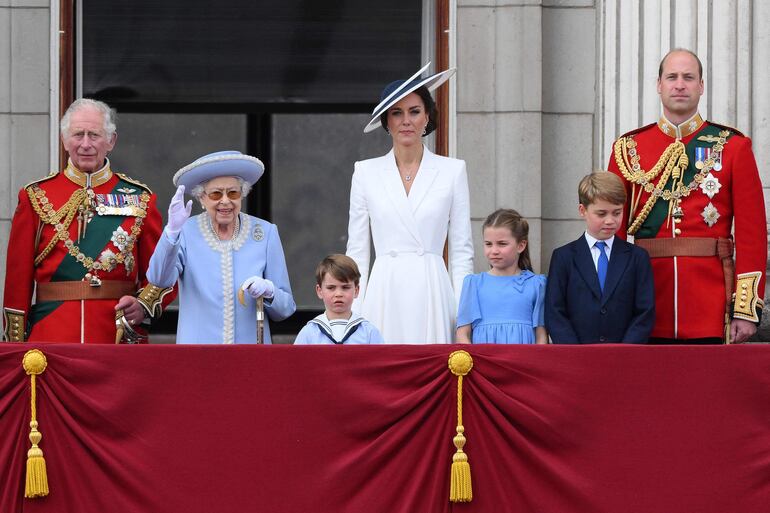 La reina Isabel II apareció en el balcón del Palacio de Buckingham vestida con abrigo y sombrero azul. Sonriente y de pie junto a sus hijos y nietos, herederos de la corona. (AFP)