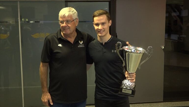 Joshua Duerksen, junto a su padre Ronald, este jueves tras su arribo al aeropuerto Silvio Pettirossi, con el trofeo en la mano.