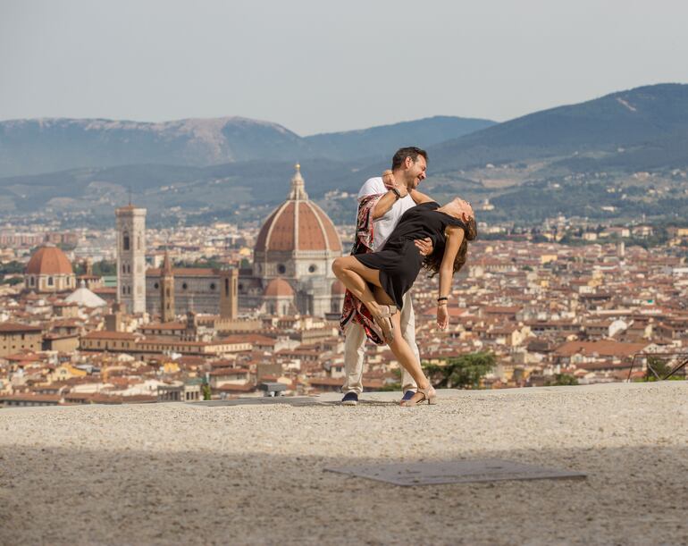 Pareja romántica bailando con el Duomo de fondo, Florencia, Italia.