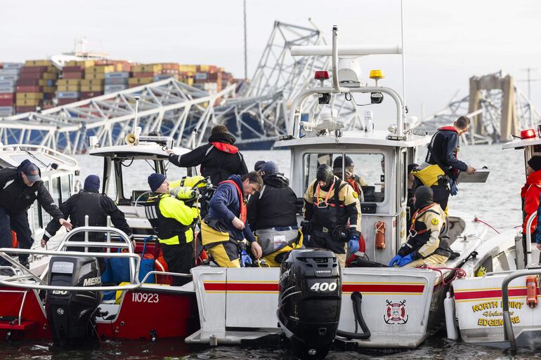 El personal de rescate se reúne en la orilla del río Patapsco después de que un buque portacontenedores chocara contra el puente Francis Scott Key (atrás) provocando su colapso en Baltimore, Maryland, EE.UU., 26 de marzo de 2024.