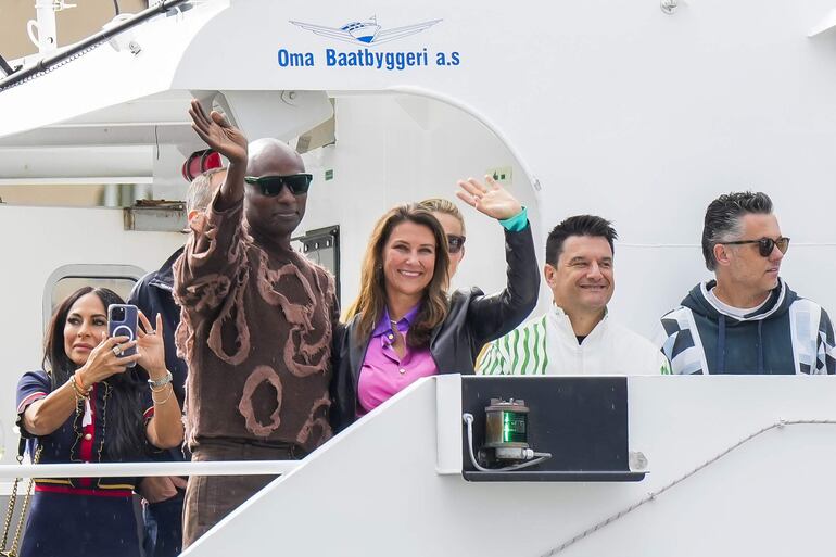 La princesa noruega Marta Luisa y su pareja Durek Verrett saludan al llegar a los barcos que los transportaron a la celebración de su boda, en Alesund, al oeste de Noruega. (EFE/EPA/HEIKO JUNGE)
