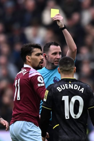 (FILES) English referee Chris Kavanagh shows a yellow card to West Ham United's Brazilian midfielder Lucas Paqueta (L) during the English Premier League football match between West Ham United and Aston Villa at the London Stadium, in London on March 12, 2023. West Ham midfielder Lucas Paqueta has been charged with alleged breaches of Football Association betting rules after a probe into claims the Brazilian deliberately earned yellow cards. Paqueta has been charged with four breaches of FA rules in relation to his conduct in West Ham's Premier League matches against Leicester in November 2022, Aston Villa in March 2023, Leeds in May 2023 and Bournemouth in August 2023. (Photo by Ben Stansall / AFP) / RESTRICTED TO EDITORIAL USE. No use with unauthorized audio, video, data, fixture lists, club/league logos or 'live' services. Online in-match use limited to 120 images. An additional 40 images may be used in extra time. No video emulation. Social media in-match use limited to 120 images. An additional 40 images may be used in extra time. No use in betting publications, games or single club/league/player publications. / 