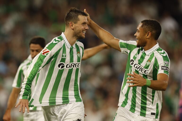 El centrocampista del Betis Giovani Lo Celso (i) celebra con Vitor Roque tras marcar ante el Espanyol, durante el partido de LaLiga en Primera División que Real Betis y RCD Espanyol disputan este domingo en el estadio Benito Villamarín, en Sevilla.