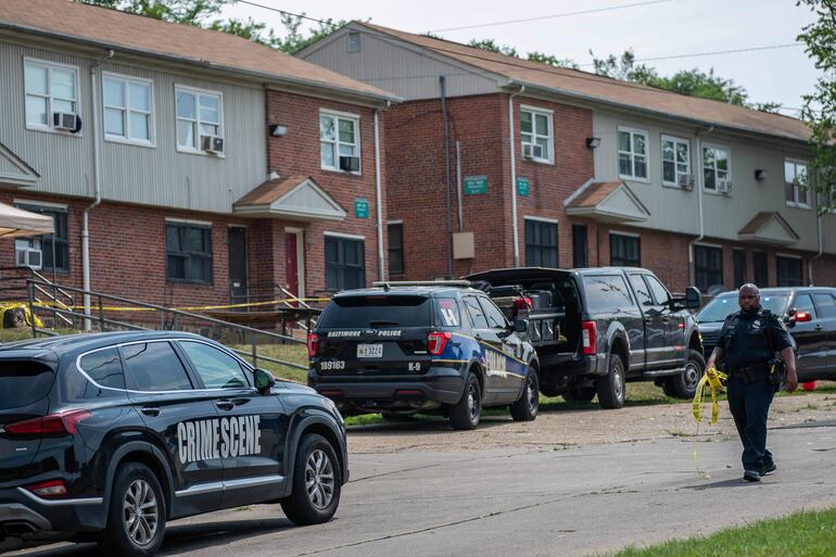 Un oficial de policía de Baltimore cuelga una cinta policial en el lugar de un tiroteo masivo en el vecindario de Brooklyn Homes el 2 de julio de 2023 en Baltimore, Maryland. Al menos dos personas murieron y otras 28 resultaron heridas durante el tiroteo en una fiesta de barrio el sábado por la noche.