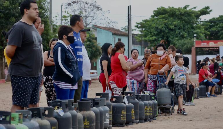 Larga fila de ciudadanos esperando recargar sus garrafas sin ningún costo.