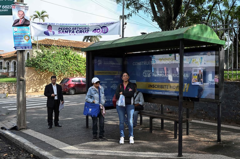 Political advertising is seen while people wait at a bus stop in Asuncion on April 26, 2023. - Paraguay holds general and presidential elections on April 30, 2023. (Photo by Luis ROBAYO / AFP)