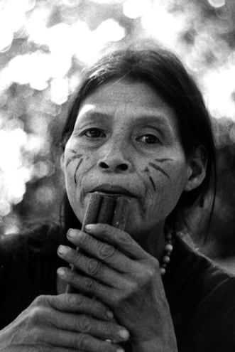 Mujer mbya tocando un instrumento de viento.