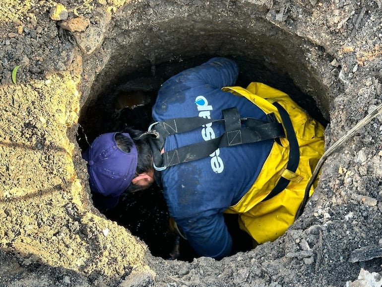 Funcionario de la Essap trabajando dentro de un alcantarillado.