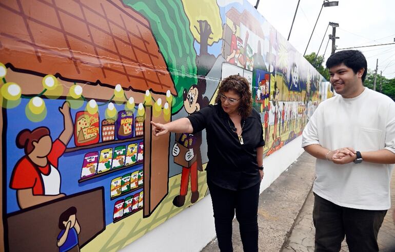 Directiva de Mickey y artista observan mural conmemorativo.