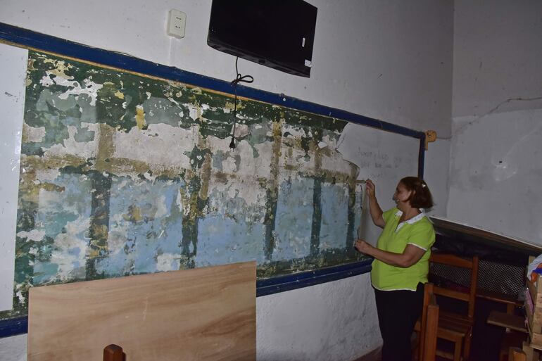 Profesora muestra la pizarra destrozada en un grado de la escuela.