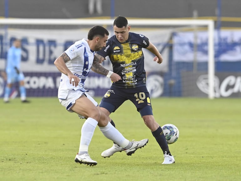 Abel Paredes, jugador de Sportivo Ameliano, y Diego Torres, futbolista de Sportivo Trinidense, pelean por el balón en un partido del fútbol paraguayo en el estadio Martín Torres, en Asunción, Paraguay.