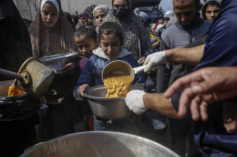 Imagen de archivo. Niños palestinos desplazados reciben alimentos proporcionados por donantes árabes y palestinos en la ciudad de Deir al Balah, al sur de la Franja de Gaza, el 24 de febrero de 2024.