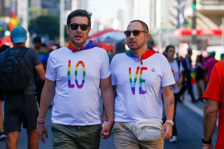 Una pareja gay pasea tomada de las manos en una marcha por el Día del Orgullo. 