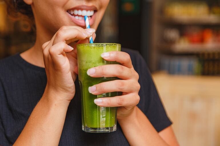 Mujer bebe un jugo verde.