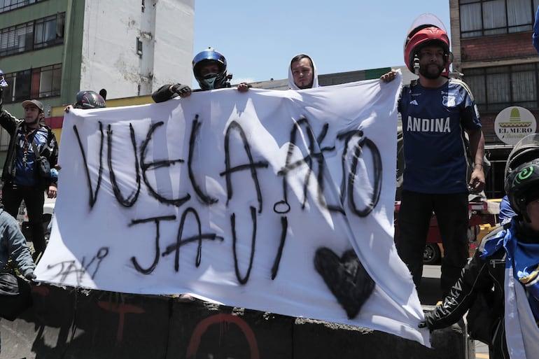 Integrantes de la barra Comandos Azules del equipo colombiano Millonarios alientan afuera del hospital San Ignacio para despedir a Javier Acosta este viernes, en Bogotá (Colombia). 