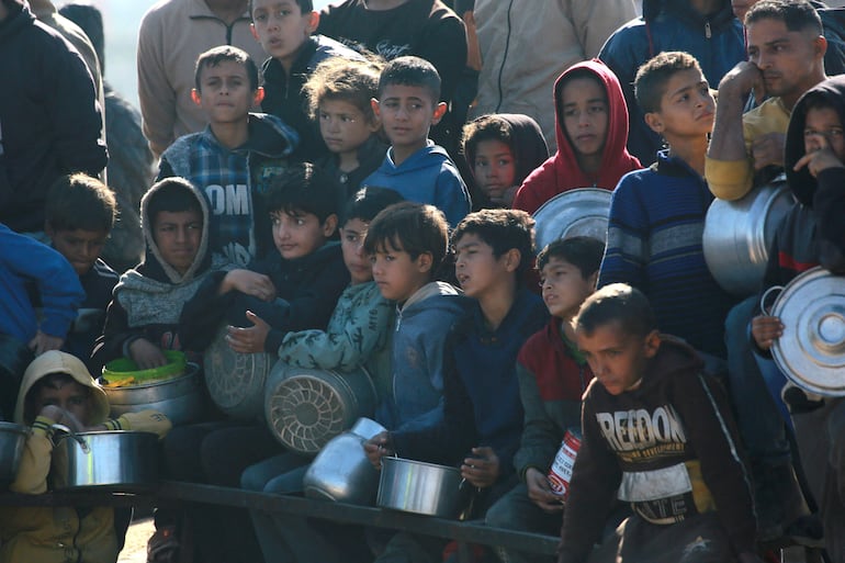 Palestinos esperan una ración de comida en un centro de distribución al sur de Khan Yunis, en el sur de la Franja de Gaza, en medio de la guerra en curso entre Israel y el movimiento palestino Hamás.