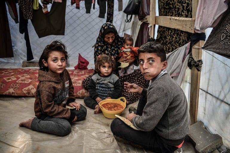 Muhammad, de 11 años, con su madre Samar, de 32 años, y sus tres hermanas sentadas alrededor de un plato de frijoles en su tienda de campaña en Rafah, al sur de la Franja de Gaza. Samar sufre de leucemia y no hay tratamiento disponible para ella debido a la guerra en curso en la Franja de Gaza.  