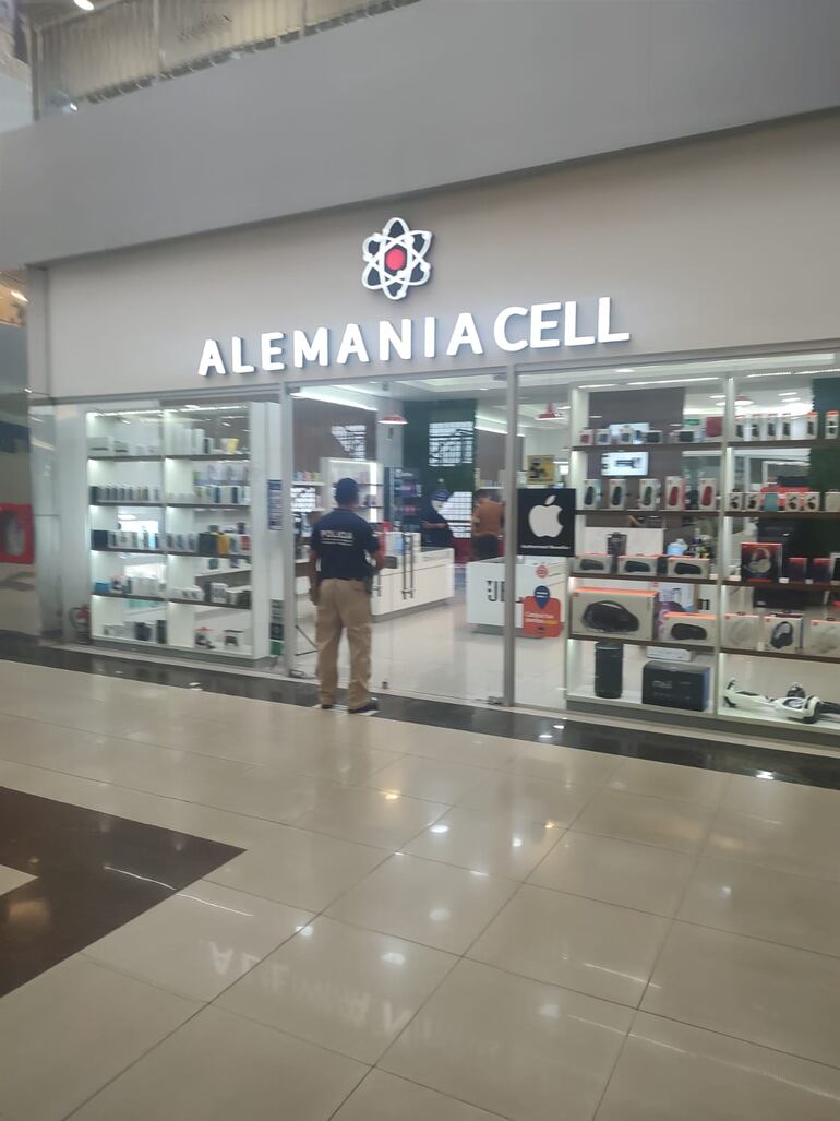 Un agente policial se dispone a ingresar a la tienda "Alemania Cell" para detener a los supuestos implicados en el esquema de estafa.