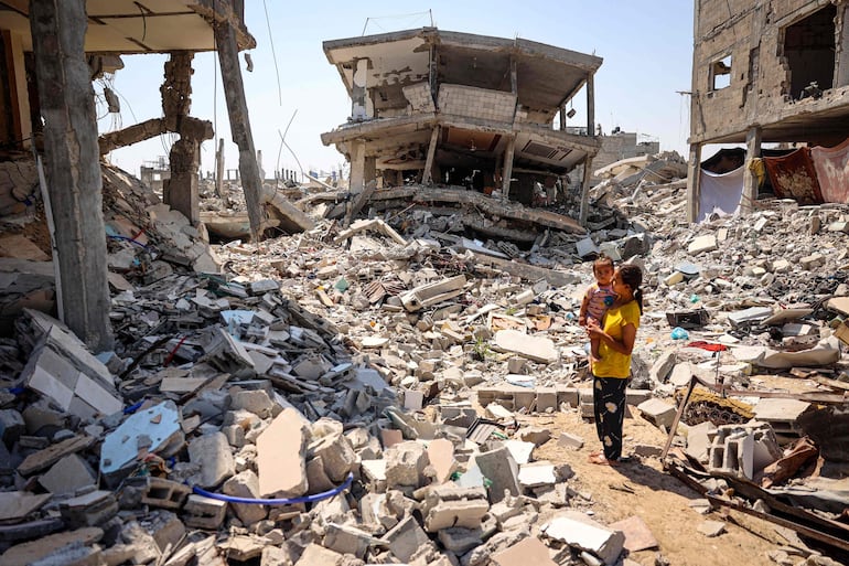 Una mujer y un niño entre los escombros de edificios destruidos por un bombardeo israelí en Jan Yunis, en el sur de la Franja de Gaza, este domingo.

