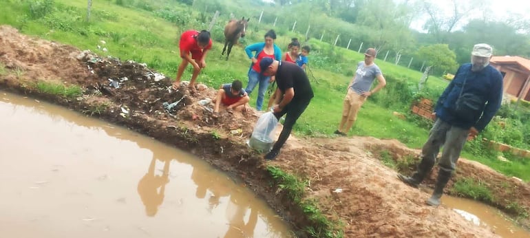 La productora Graciela Estigarribia acompañada de sus hijos y el Ing. Sergio Gómez, observa el momento del cultivo de los primeros alevines de tilapia en su estanque.