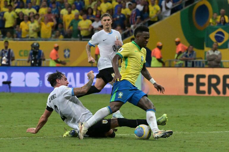 Uruguay's defender #02 Jose Maria Gimenez and Brazil's forward #07 Vinicius Jr fight for the ball during the 2026 FIFA World Cup South American qualifiers football match between Brazil and Uruguay at the Arena Fonte Nova stadium in Salvador, Brazil, on November 19, 2024. (Photo by NELSON ALMEIDA / AFP)