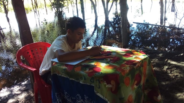 Un alumno realiza tareas escolares en el único lugar seco de la casa. Tacuaras - Ñeembucú.