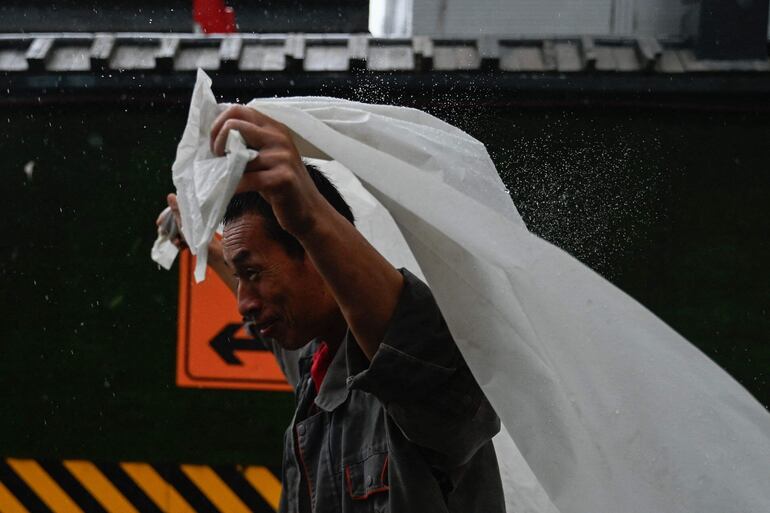 Un hombre se protege de la lluvia con una cortina de plástico en Pekín, China, el domingo.