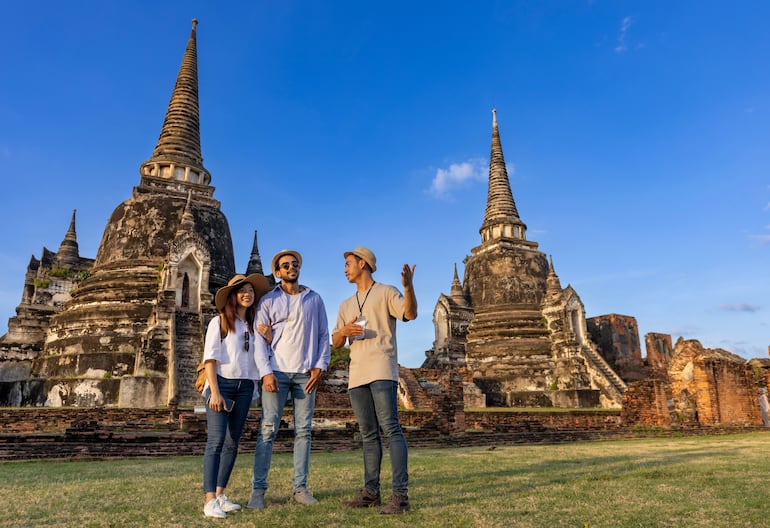 Guía local tailandés explica la historia del viejo Siam a pareja de turistas.