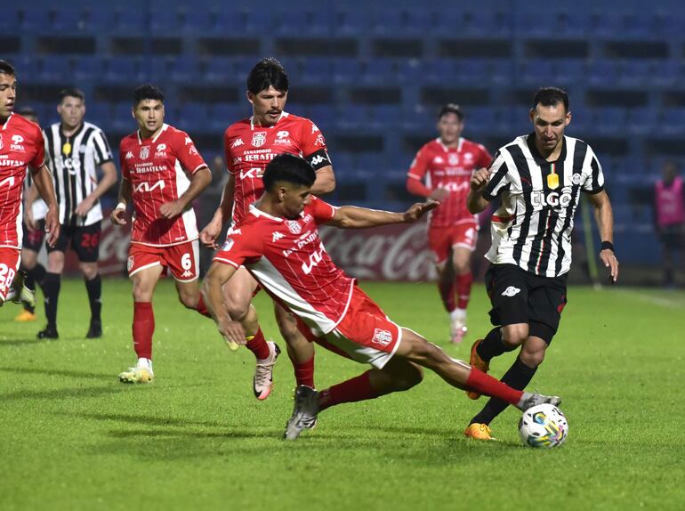 El zaguero Éver Alejandro Fernández barre a los pies del extremo Marcelo Fernández buscando hacerse con el esférico. El capitán rojo, Fernando “Chapa” Martínez, sigue de cerca la acción.