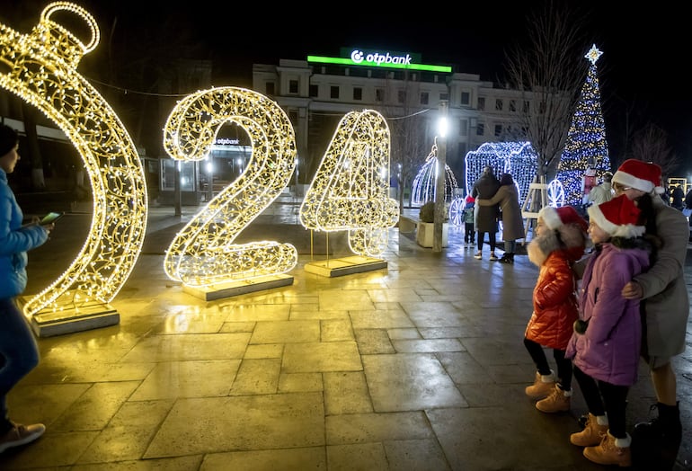 Chisinau (Moldavia, República de), 31/12/2023.- La gente se hace fotos en la plaza del Organi, decorada con luces navideñas, durante una celebración de Nochevieja en Chisinau, Moldavia, el 31 de diciembre de 2023. Los habitantes de los antiguos países de la Unión Soviética disfrutan del Año Nuevo en dos ocasiones, el 31 de diciembre y el 14 de enero. (Moldavia) EFE/EPA/DUMITRU DORU
