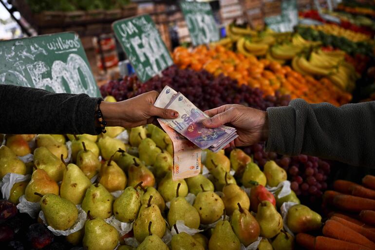 Un hombre paga en efectivo frutas y verduras en un mercado de Buenos Aires. 